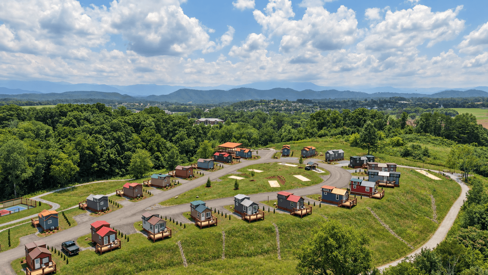 Daylight aerial view of Sojourn's colorful tiny-home village with the Smoky Mountains beyond