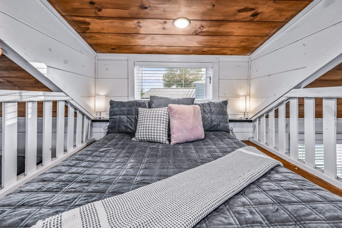 Loft sleeping area with gray quilt and pink accents